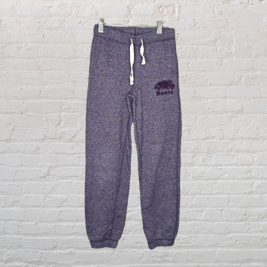 Purple Roots sweatpants with drawstring waist and logo on a white brick background.