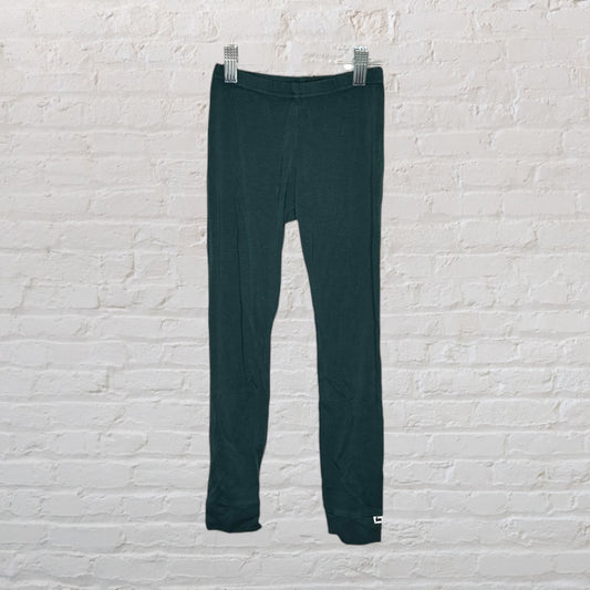 Dark green leggings hanging on a background clip against a white brick wall.