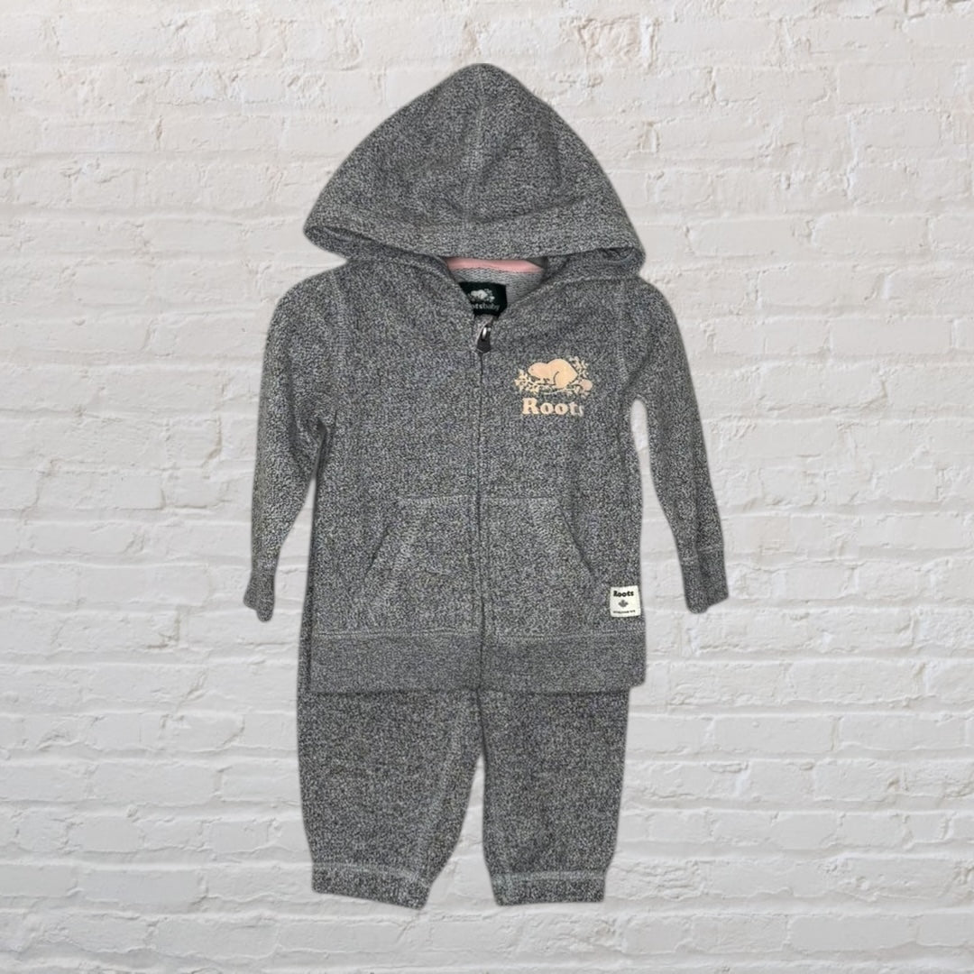 Heather grey Roots hoodie and pants set for kids with logo on the chest, displayed against a brick wall.