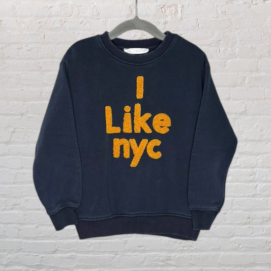 Black sweatshirt with 'I Like nyc' embroidered in orange text, hanging on a hanger.