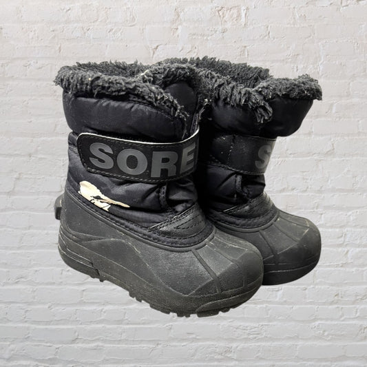 Black Sorel winter boots with faux fur lining and velcro straps, showing signs of wear.