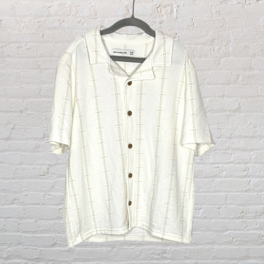 Off-white short sleeve button-up shirt with textured pattern, displayed on a hanger.