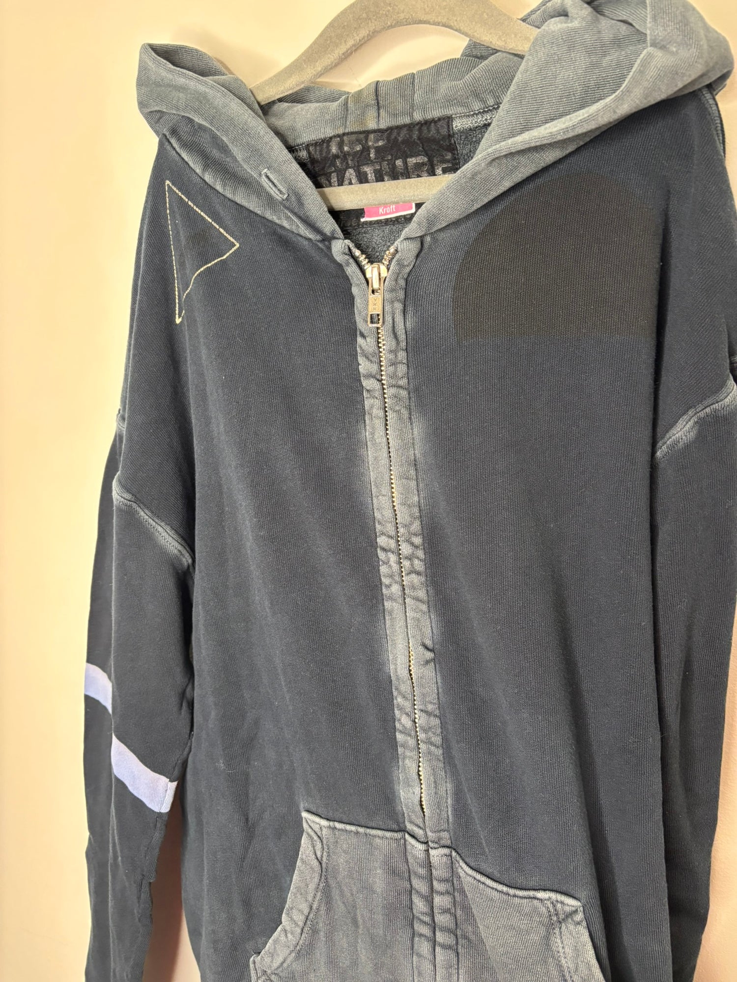 Black and grey hoodie with 'We Are of the Garden' text and graphic design on the back, displayed on a hanger.