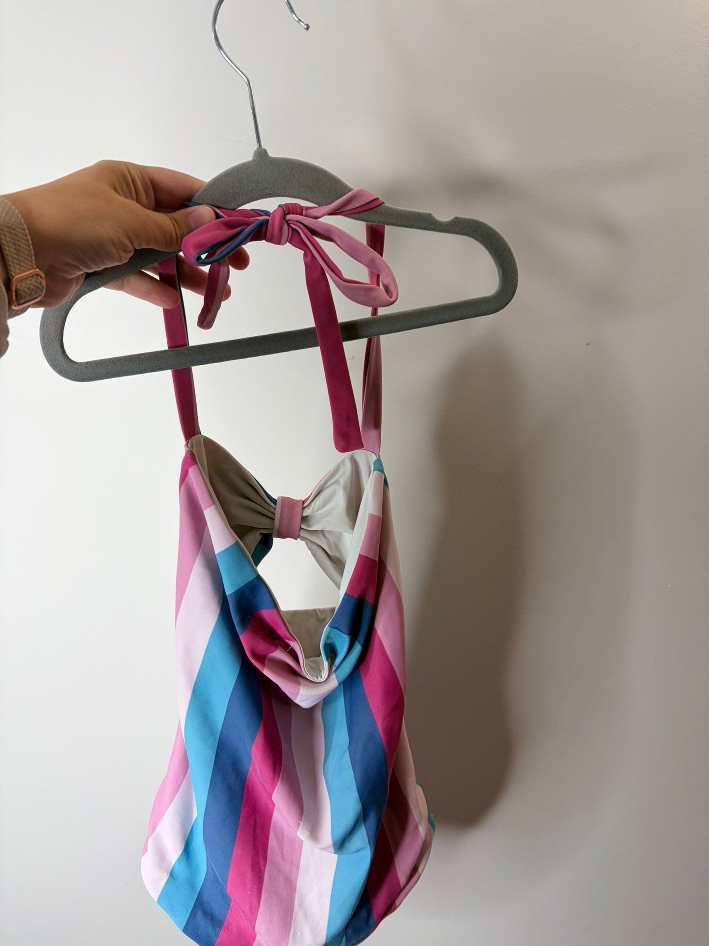 Women's one-piece swimsuit with pink, blue, and white vertical stripes, featuring a cut-out design and bow detail.
