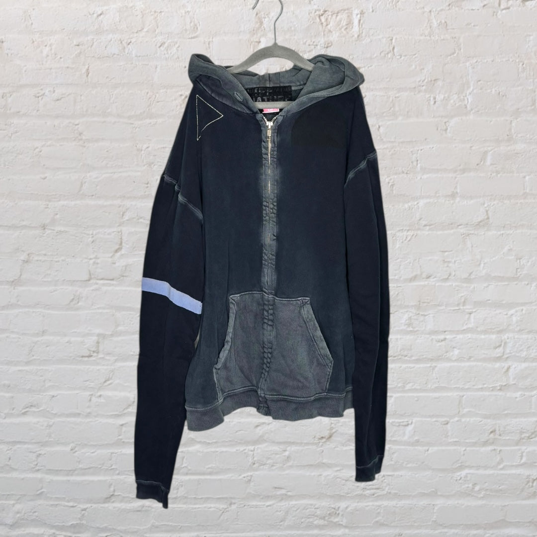 Black and grey hoodie with 'We Are of the Garden' text and graphic design on the back, displayed on a hanger.