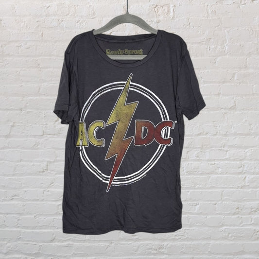 Faded black t-shirt with a vintage AC/DC logo featuring a lightning bolt design, hanging on a hanger.