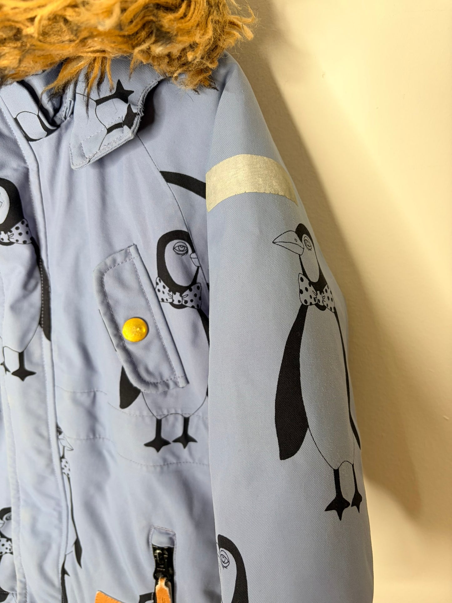 Grey parka with penguin print, featuring a faux fur trimmed hood and reflective patch on the sleeve.